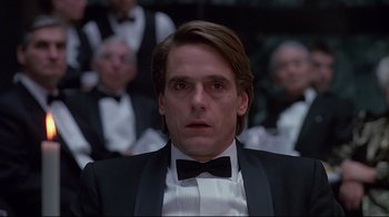 Movie still from “Dead Ringers” (1988), directed by David Cronenberg – A man in a suit and bow tie in front of a group of people; Close Up shot, Low angle