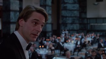 Movie still from “Dead Ringers” (1988), directed by David Cronenberg – A man standing in front of a crowd of people; Close Up shot, Over the shoulder angle