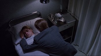 Movie still from “Dead Ringers” (1988), directed by David Cronenberg – A man and woman laying in a hospital bed next to each other; Medium shot, High angle