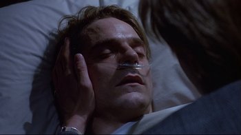 Movie still from “Dead Ringers” (1988), directed by David Cronenberg – A man laying in a hospital bed with a thermometer in his mouth; Close Up shot, Over the shoulder angle