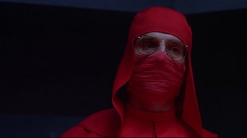 Movie still from “Dead Ringers” (1988), directed by David Cronenberg – A man in a red outfit with a face mask; Close Up shot, Low angle