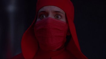 Movie still from “Dead Ringers” (1988), directed by David Cronenberg – A person wearing a red cloth and a red hat; Close Up shot, Low angle