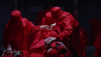 Movie still from “Dead Ringers” (1988), directed by David Cronenberg – A group of people dressed in bright red robes; Medium shot, Overhead angle