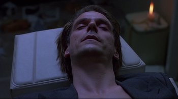 Movie still from “Dead Ringers” (1988), directed by David Cronenberg – A man laying on top of a bed with his eyes closed; Close Up shot, High angle
