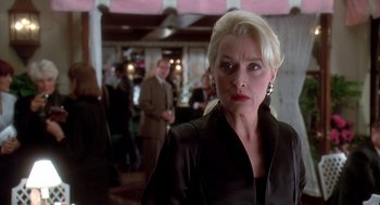 Movie still from “Death Becomes Her” (1992), directed by Robert Zemeckis – An older woman with blonde hair wearing a black jacket; Close Up shot, Over the shoulder angle