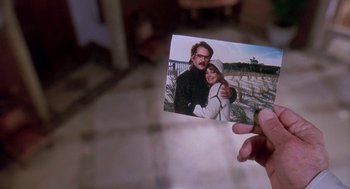 Movie still from “Death Becomes Her” (1992), directed by Robert Zemeckis – A person holding a picture of a man and a woman; Extreme Close Up shot, High angle