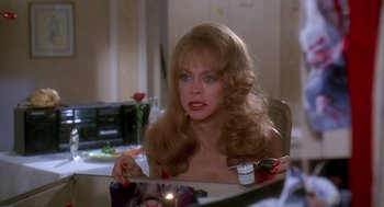 Movie still from “Death Becomes Her” (1992), directed by Robert Zemeckis – A woman sitting in front of a mirror holding a brush; Medium shot, Over the shoulder angle