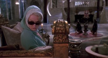 Movie still from “Death Becomes Her” (1992), directed by Robert Zemeckis – An older woman sitting in front of a table with candles; Medium shot, Over the shoulder angle