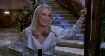 Movie still from “Death Becomes Her” (1992), directed by Robert Zemeckis – A woman with long blonde hair waving at the camera; Medium shot, Over the shoulder angle