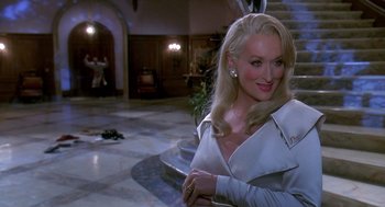 Movie still from “Death Becomes Her” (1992), directed by Robert Zemeckis – A woman with blonde hair wearing a white jacket; Close Up shot, Over the shoulder angle