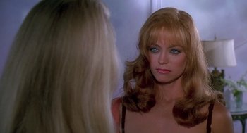 Movie still from “Death Becomes Her” (1992), directed by Robert Zemeckis – A woman looking into a mirror while standing next to a wall; Close Up shot, Over the shoulder angle