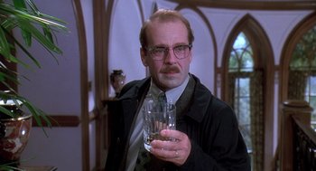 Movie still from “Death Becomes Her” (1992), directed by Robert Zemeckis – A man holding a glass of water in his hand; Close Up shot, Low angle