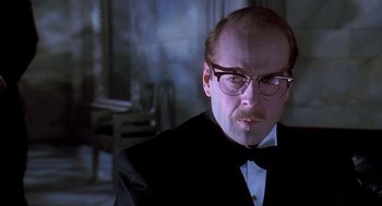 Movie still from “Death Becomes Her” (1992), directed by Robert Zemeckis – A man in a suit and bow tie wearing glasses; Close Up shot, Low angle