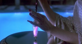 Movie still from “Death Becomes Her” (1992), directed by Robert Zemeckis – A woman's hand is holding a drink in a glass; Extreme Close Up shot, Over the shoulder angle