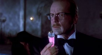 Movie still from “Death Becomes Her” (1992), directed by Robert Zemeckis – A man in a tuxedo holding a glass of pink liquid; Close Up shot, Low angle
