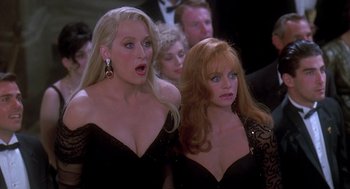 Movie still from “Death Becomes Her” (1992), directed by Robert Zemeckis – Two women in black dresses one of which is looking surprised; Close Up shot, Over the shoulder angle
