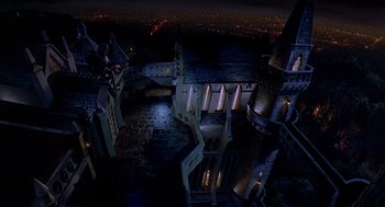 Movie still from “Death Becomes Her” (1992), directed by Robert Zemeckis – An aerial view of a castle at night with lights on it; Extreme Wide shot, High angle