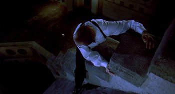 Movie still from “Death Becomes Her” (1992), directed by Robert Zemeckis – A man in a white shirt and black pants climbing a wall; Wide shot, Overhead angle