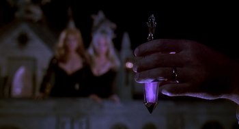 Movie still from “Death Becomes Her” (1992), directed by Robert Zemeckis – A person holding a purple light in their hand; Extreme Close Up shot, High angle