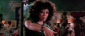 Movie still from “Death Proof” (2007), directed by Quentin Tarantino – A woman in a green t - shirt is looking at her watch; Close Up shot, Low angle