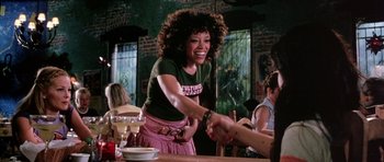 Movie still from “Death Proof” (2007), directed by Quentin Tarantino – A woman shaking hands at a table in a restaurant; Medium shot, Over the shoulder angle