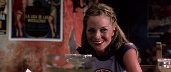 Movie still from “Death Proof” (2007), directed by Quentin Tarantino – A woman smiles while sitting at a table with food; Close Up shot, Low angle