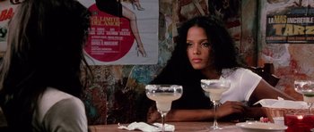 Movie still from “Death Proof” (2007), directed by Quentin Tarantino – A woman sitting at a table with two glasses of wine; Close Up shot, Over the shoulder angle