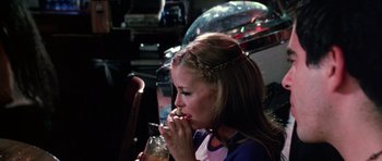 Movie still from “Death Proof” (2007), directed by Quentin Tarantino – A woman sitting in front of a glass of water; Medium shot, Over the shoulder angle