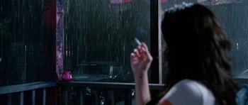Movie still from “Death Proof” (2007), directed by Quentin Tarantino – A woman holding up a cigarette in front of an open window; Medium shot, Over the shoulder angle
