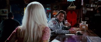 Movie still from “Death Proof” (2007), directed by Quentin Tarantino – Two people sitting at a table in front of each other holding drinks; Medium shot, Over the shoulder angle