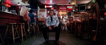 Movie still from “Death Proof” (2007), directed by Quentin Tarantino – A man sitting on a chair in a bar; Wide shot, Low angle