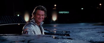 Movie still from “Death Proof” (2007), directed by Quentin Tarantino – A man sitting on top of a boat in the water at night; Close Up shot, Low angle