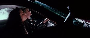 Movie still from “Death Proof” (2007), directed by Quentin Tarantino – A woman sitting in the driver's seat of a car at night; Medium shot, Low angle