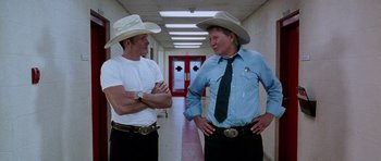 Movie still from “Death Proof” (2007), directed by Quentin Tarantino – A couple of men standing next to each other in a hallway; Medium shot, Low angle