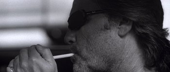 Movie still from “Death Proof” (2007), directed by Quentin Tarantino – A person wearing sunglasses and smoking a cigarette; Extreme Close Up shot, Low angle