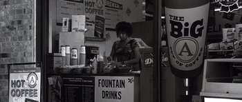 Movie still from “Death Proof” (2007), directed by Quentin Tarantino – A woman sitting at a counter in front of drinks; Wide shot, High angle