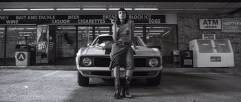 Movie still from “Death Proof” (2007), directed by Quentin Tarantino – A woman standing in front of an old muscle car; Wide shot, Low angle