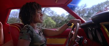 Movie still from “Death Proof” (2007), directed by Quentin Tarantino – A woman sitting in the driver's seat of a red car; Medium shot, Low angle
