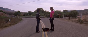 Movie still from “Death Proof” (2007), directed by Quentin Tarantino – Two women standing on the side of the road talking; Wide shot, Low angle