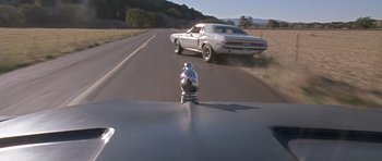 Movie still from “Death Proof” (2007), directed by Quentin Tarantino – A car driving down a road next to a fire hydrant; Wide shot, High angle