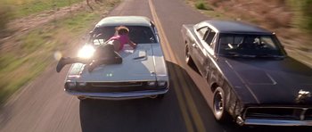 Movie still from “Death Proof” (2007), directed by Quentin Tarantino – A woman sitting on the hood of an old car; Wide shot, Low angle