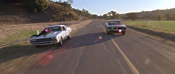 Movie still from “Death Proof” (2007), directed by Quentin Tarantino – A couple of cars driving down a street; Wide shot, Low angle