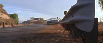 Movie still from “Death Proof” (2007), directed by Quentin Tarantino – A car driving down a road next to a train track; Wide shot, Low angle