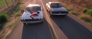 Movie still from “Death Proof” (2007), directed by Quentin Tarantino – A couple of cars driving down a street; Wide shot, Overhead angle