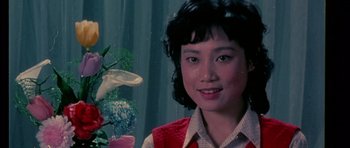 Movie still from “Death Proof” (2007), directed by Quentin Tarantino – A person wearing a jacket near a flower; Close Up shot, Low angle