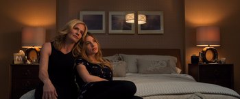 Movie still from “Death Wish” (2018), directed by Eli Roth – Two women sitting on a couch in a living room; Medium shot, High angle