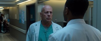 Movie still from “Death Wish” (2018), directed by Eli Roth – A man wearing a white lab coat looking into a mirror; Close Up shot, Over the shoulder angle