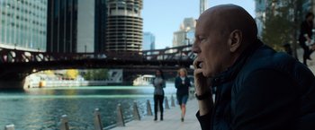Movie still from “Death Wish” (2018), directed by Eli Roth – A man on a cell phone in front of a bridge; Medium shot, Over the shoulder angle