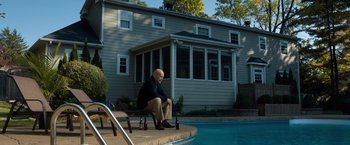 Movie still from “Death Wish” (2018), directed by Eli Roth – A man sitting on top of a bench next to a swimming pool; Wide shot, High angle