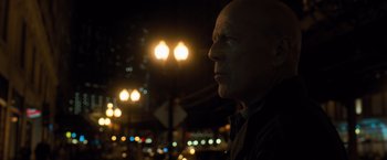 Movie still from “Death Wish” (2018), directed by Eli Roth – A man standing in front of street lights at night; Close Up shot, Over the shoulder angle